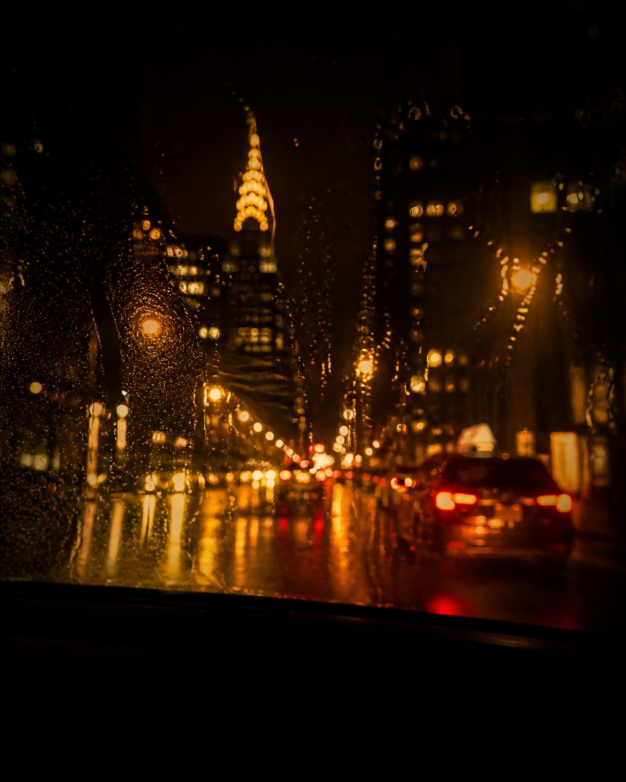 City lights blurred through a rain-covered windshield at night